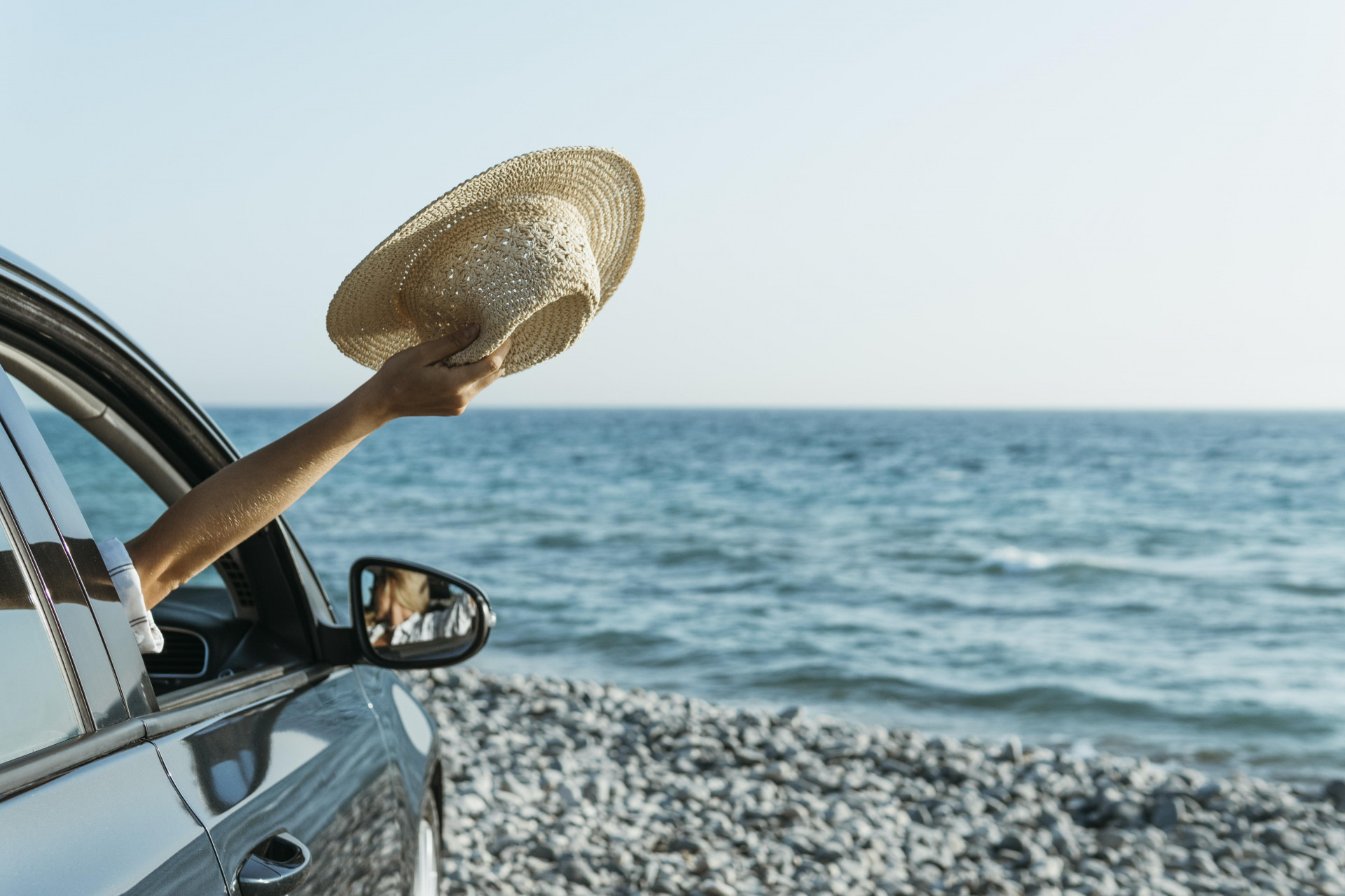 mid-shot-woman-hand-out-car-window-holding-hat-near-sea-1249
